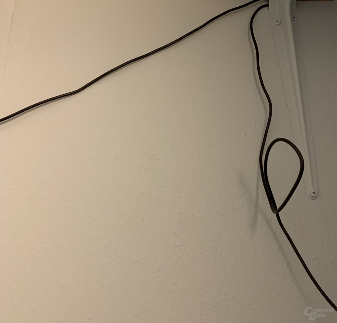 Schwarzes Kabel vor weißer Wand